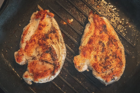 Crispy golden chicken with skin on being fried on a black griddle in hot oilの写真素材