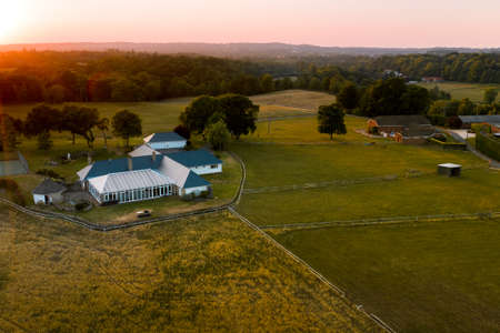 Aerial shot of Peaceful rural farmland during sunset in summer in the UK with fields of farmland and meadow with pink skiesの写真素材