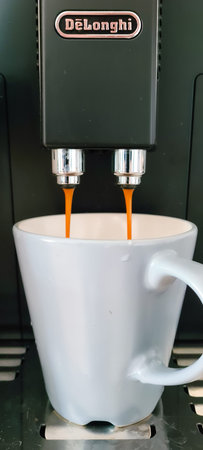 Aldershot, UK - 31st March 2020: Close up of DeLonghi coffee machine pouring a fresh cup of coffee automatically into a washed mug for a morning routineのeditorial素材