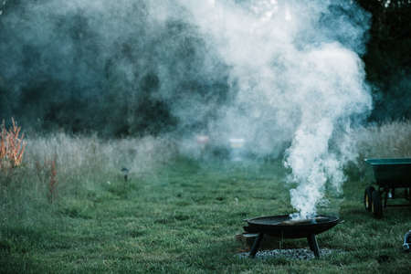 Smoke from a burning cooking camp fire from holiday makers in dark greenの写真素材