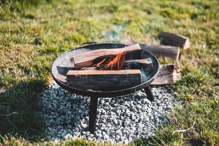 Close up of a cooking camp fire burning on grass safely on stonesの写真素材
