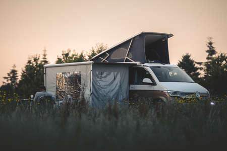 Chester, Cheshire - 17th July 2021: A VW camp van used for camping with a man relaxing drinking wine whilst camping at sunsetのeditorial素材