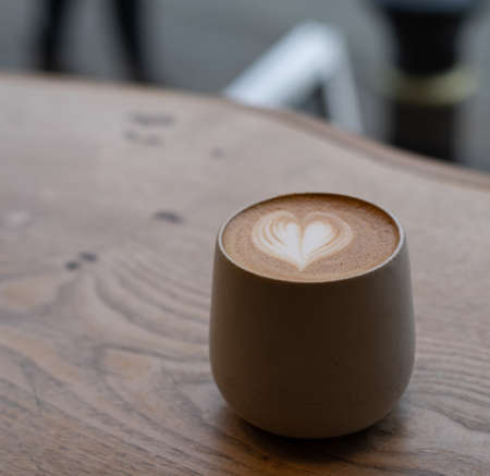 Flat White coffee with leaf in a cup on a wooden table with room for textの写真素材