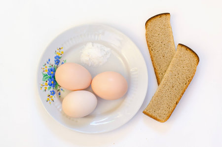 Eggs on the plate with bread and salt.の写真素材
