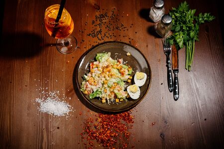 Caesar salad on black plate on wooden table.plate with fresh caesar salad with chicken on old wooden table.Top viewの写真素材