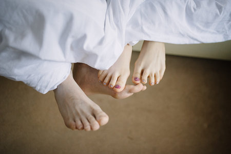 Feet of man and woman in bed in the morning close-up