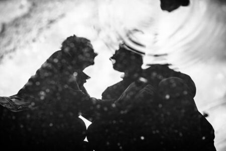 Reflection of a man and woman in a puddle on the roadの写真素材