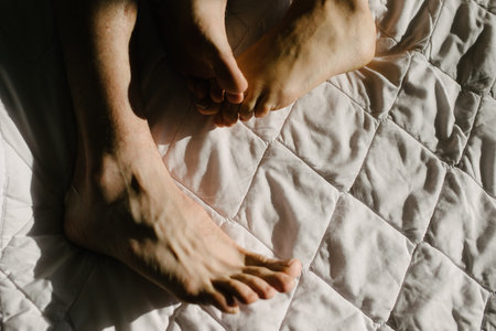 Feet of man and woman in bed in the morning close-up