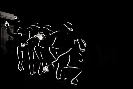 People in luminous costumes dance in the dark for a holiday