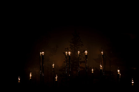 Burning wax candle in the dark in church close up