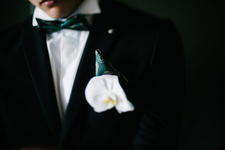 A man in a suit straightens his boutonniere