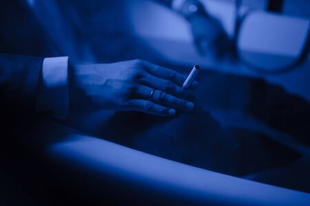 A man in a suit lies in a bath of water and smokesの写真素材