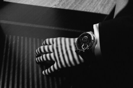 A man in a suit adjusts the clock on his handの写真素材