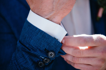Man in suit straightens shirt sleeve