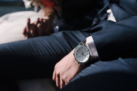 A man in a suit adjusts the clock on his handの写真素材