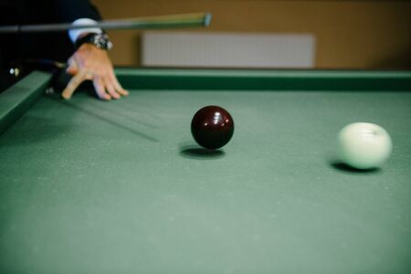 A man in a black suit plays billiards indoorsの写真素材