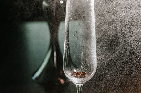 Wedding rings of the bride and groom are in the glass close-upの写真素材