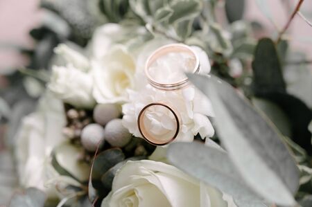 Wedding rings of the bride and groom are on the flowers closeupの写真素材