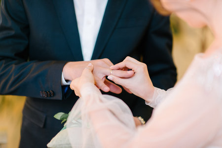 The bridegroom puts the wedding ring on the bride close up.
