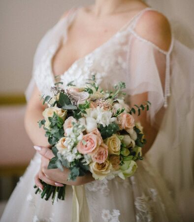 Bride in a wedding dress holding a wedding bouquet in her handsの写真素材