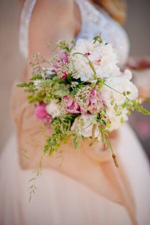 Bride in a wedding dress holding a wedding bouquet in her handsの写真素材