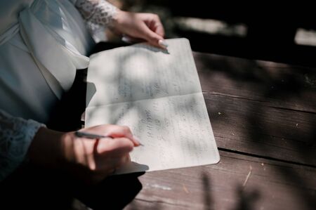 The bride holds a love letter. Wedding ceremony. The bride reads the wedding letter at the wedding ceremony.の写真素材