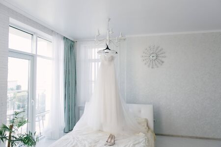 White wedding dress hanging in the bedroom. White bride dress close upの写真素材