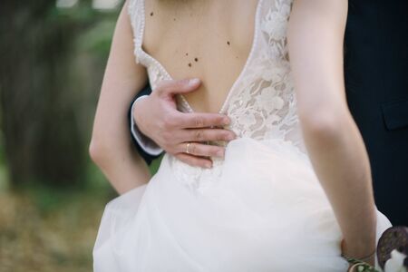 The groom in a suit hugs the bride in a wedding dress close upの写真素材