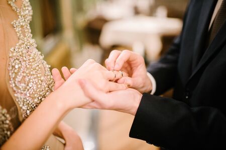 The bridegroom puts the wedding ring on the bride close up.の販売画像