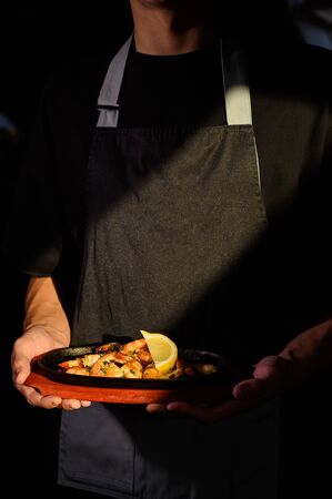 The waiter holds on a tray a dish with shrimps and a glass of beerの写真素材