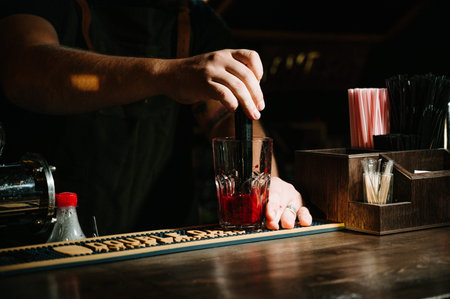 Bartender makes the fresh and sweet strawberry mojito summer cocktail on the dark background