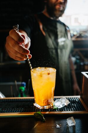 Bartender stirring a sweet and fresh orange summer cocktail in glass on the bar counterの写真素材