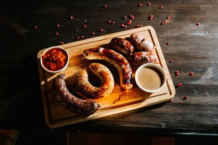 Delicious grilled sausages with sauces on wooden tray, top view. Barbecue foodの写真素材