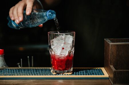 Bartender makes the fresh and sweet strawberry mojito summer cocktail on the dark backgroundの写真素材