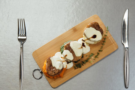 Melted cheese on meat patties on a cutting board on the table