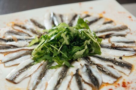 Freshly Spiced Sprat with Greens on a Plate on the Tableの写真素材