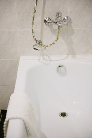 Steel hanging shower in a white marble bathroom close-up