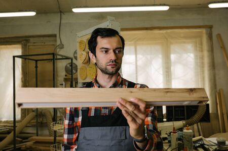 Working process in the carpentry workshop.A man in overalls works in a carpentry workshop.Profession, carpentry, woodwork and people conceptの写真素材