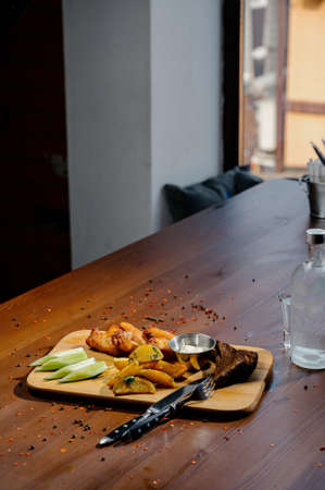 Barbecue grilled chicken wings close up with fries, sauce on wooden board on a dark background. Meat food concept.Fried chicken legs with french friesの写真素材