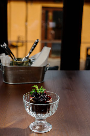 chocolate ice cream with berry jam in glass cup on black background