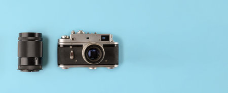 Retro photo camera with lens on blue background, flat lay