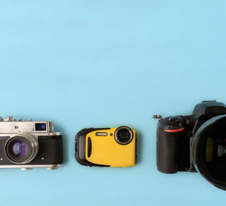 Camera evolution.Cameras of different types and generations on a blue background, top view, flat lay. Three cameras of different generations on a blue background. Technological progress of camerasの写真素材