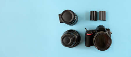 Photographer's equipment. Flat lay composition with photographer's equipment and accessories on yellow background.Camera, lenses and spare batteries on a blue background, top view.の写真素材