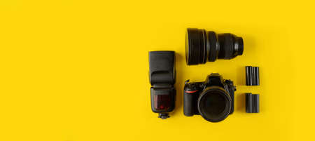 Photographer's equipment. Flat lay composition with photographer's equipment and accessories on yellow background.Camera, lens, flash and batteries on a yellow background, top view.の写真素材