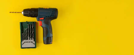 cordless drill, screwdriver with drill bit on yellow background, top view. Drill with drills of different types and sizes on a yellow background, flat layの写真素材