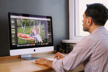Professional Photographer Works in Photo Editing App. Software on His Personal Computer.Photographer for processing photos. Photographer equipment on the table. Retouching photos.のeditorial素材
