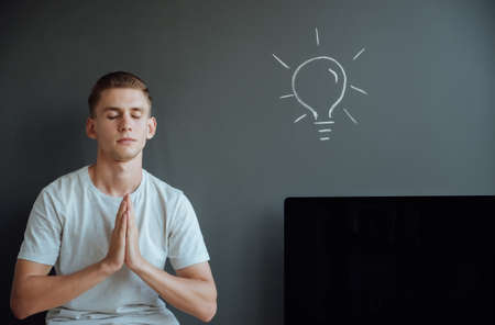 Young smiling man has an idea.Idea concept.Portrait young man has an idea, pointing with finger up on gray wall background.の写真素材