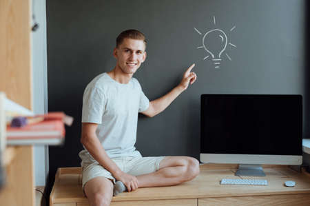Young smiling man has an idea.Idea concept.Portrait young man has an idea, pointing with finger up on gray wall background.の写真素材