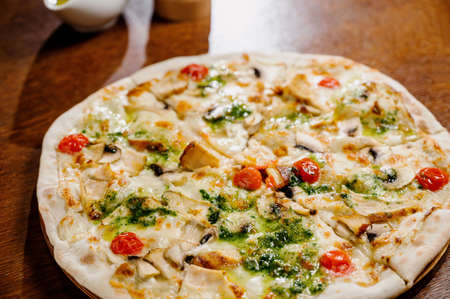 pizza with chicken, mozzarella, olives and basil top view with copy space.Pizza with chicken and pickles on a wooden backgroundの写真素材