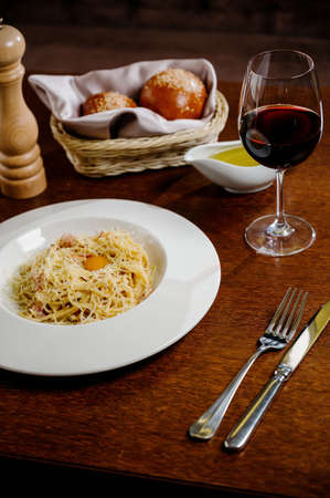 spaghetti with cheese and egg on a white plate on wooden backgroundの写真素材